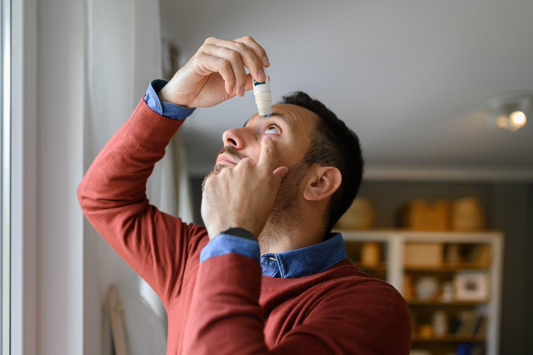 Middle aged man applying clinitas eye drops to relieve his dry eyes