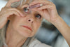 Older 60+ lady applying Clinitas hydrated carbomer gel to relieve her dry eyes