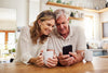 FAQ image of couple both looking and smiling at a mobile phone
